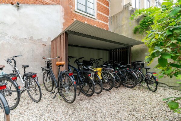 Overdekte fietsenstalling op het Lange Voorhout met meerdere geparkeerde fietsen tegen een bakstenen gevel.